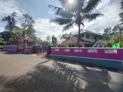 a street with a pink fence and a palm tree at Villoonnickal Homestay in Munnar