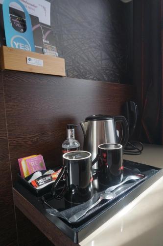 a tray with two coffee pots and pans on a table at Ambassadeur Hotel - Cherbourg Port de Plaisance in Cherbourg en Cotentin