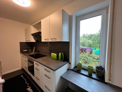a kitchen with white cabinets and a large window at Ferienwohnung Rhön Natur in Hilders