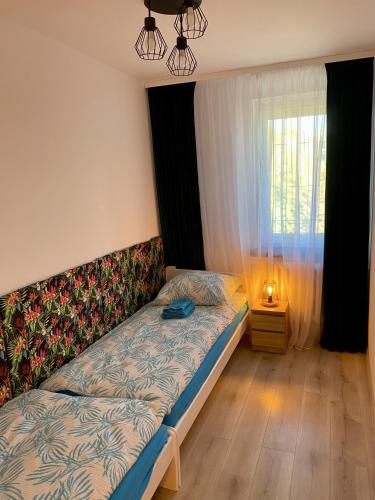 um pequeno quarto com uma cama e uma janela em Szmaragdowy Zakątek em Glogóvia