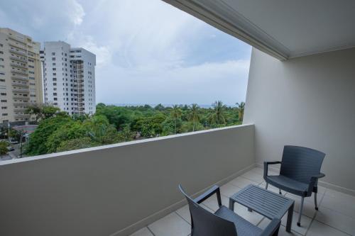 a balcony with two chairs and a view of a city at Dominican Fiesta Hotel in Santo Domingo