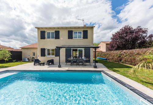 une maison avec une piscine devant une maison dans l'établissement Villa des palmiers - Magnifique villa avec piscine chauffée et terrain de pétanque, à Bon-Encontre