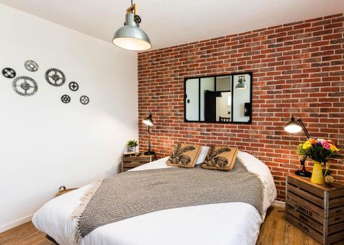 a bedroom with a brick wall and a bed at Villa des palmiers - Magnifique villa avec piscine privée et chauffée selon saison in Bon-Encontre