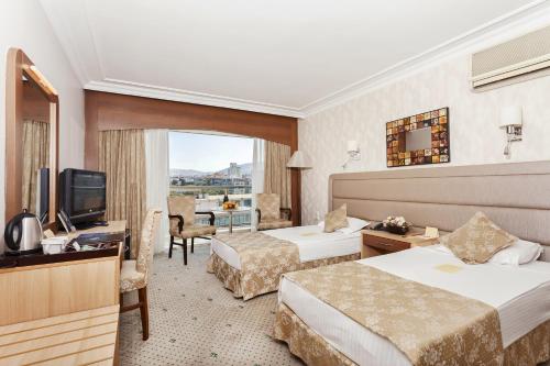 a hotel room with two beds and a television at Izmir Palas Hotel in İzmir