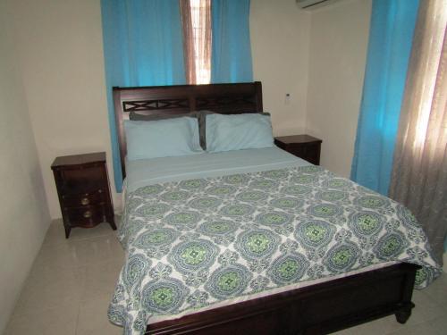 1 dormitorio con 1 cama grande y cortinas azules en Half Moon Bay, en Christ Church