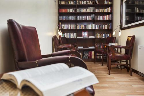 a library with chairs and a table with a book at Izmir Palas Hotel in İzmir