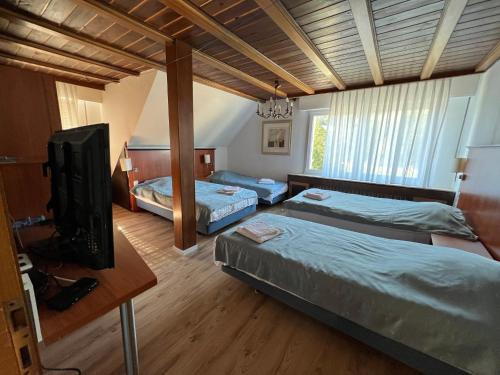 a bedroom with two beds and a flat screen tv at Hotel Restaurant Hüftgold in Plettenberg