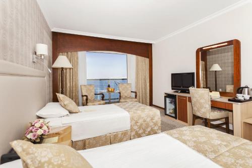 a hotel room with two beds and a desk at Izmir Palas Hotel in İzmir