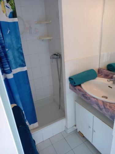 une salle de bain blanche avec une douche et un lavabo dans l'établissement Amoureva F30, T2, parking, clim, piscine, au Cap d'Agde