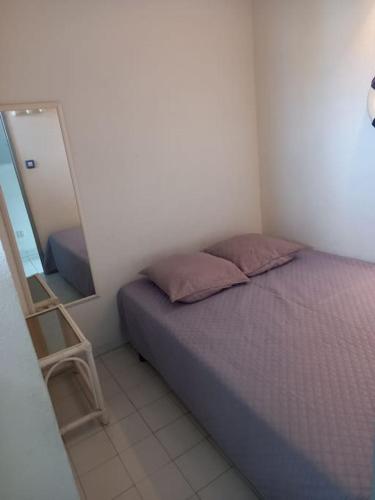 une petite chambre avec un lit et un miroir dans l'établissement Amoureva F30, T2, parking, clim, piscine, au Cap d'Agde