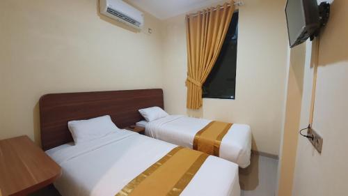 a hotel room with two beds and a window at Harmony Inn Belitung - City Hotel in Tanjungpandan