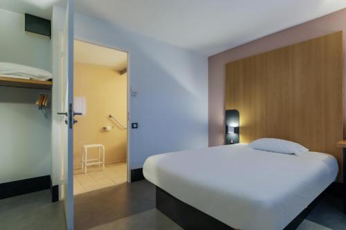 a bedroom with a large white bed and a bathroom at B&B HOTEL Metz Augny in Augny