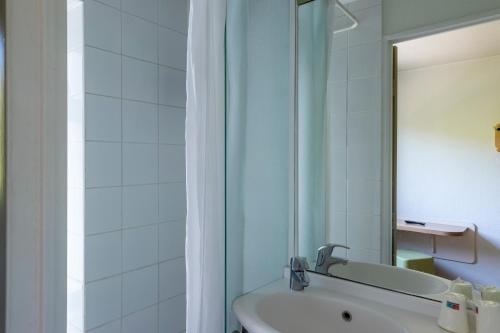 a bathroom with a tub and a sink and a mirror at B&B HOTEL Troyes Centre in Troyes