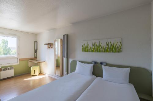 sypialnia z dużym łóżkiem z białą pościelą w obiekcie B&B HOTEL Troyes Centre w Troyes