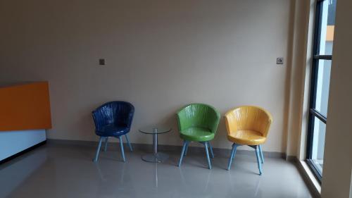 three different colored chairs sitting in a room at Harmony Inn Belitung - City Hotel in Tanjungpandan