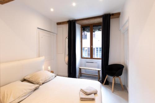 - une chambre avec un lit, une chaise et une fenêtre dans l'établissement "L'historique" - Charmant appartement en centre-ville historique, à Chambéry