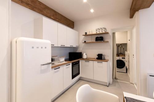 La cuisine est équipée de placards blancs et d'un réfrigérateur blanc. dans l'établissement "L'historique" - Charmant appartement en centre-ville historique, à Chambéry
