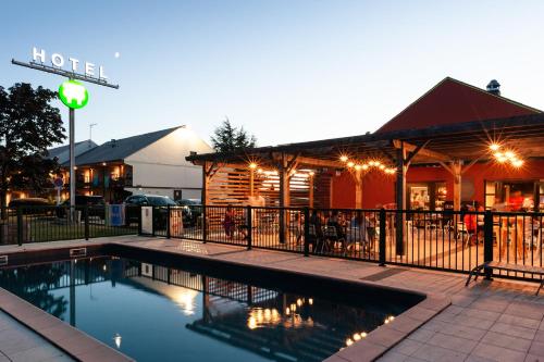 a swimming pool in front of a restaurant at Campanile Beaune in Beaune
