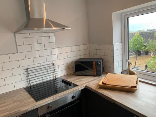 a kitchen with a counter with a microwave and a window at The Mancunian @ The Gathering - Sleeps Up To 6 in Sale