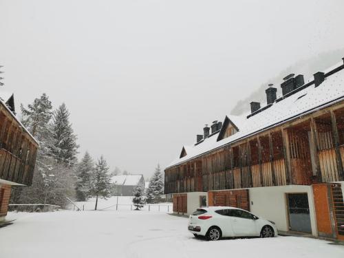 a white car parked outside of a building in the snow at Apartma M&J in Mojstrana