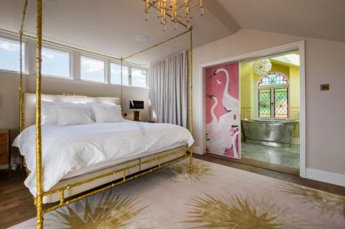 a bedroom with a bed with a gold frame and a bathroom at Downs Cottage in Deal