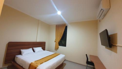 a bedroom with a bed and a television in it at Harmony Inn Belitung - City Hotel in Tanjungpandan