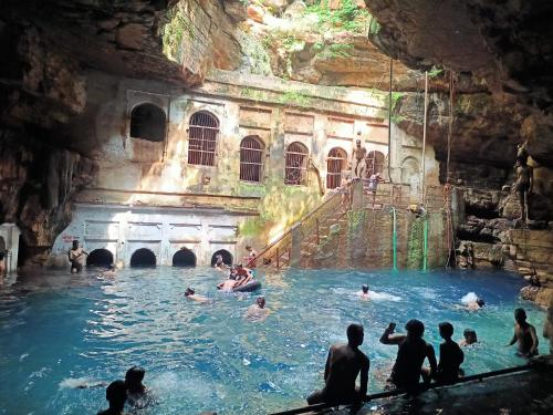 un grupo de personas en una piscina en una cueva en Khajuraho Dreams Homestay en Khajurāho