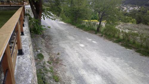 a dirt road with a wooden fence and trees at Chalet les Moineaux Chambres d'Hôtes in Jausiers