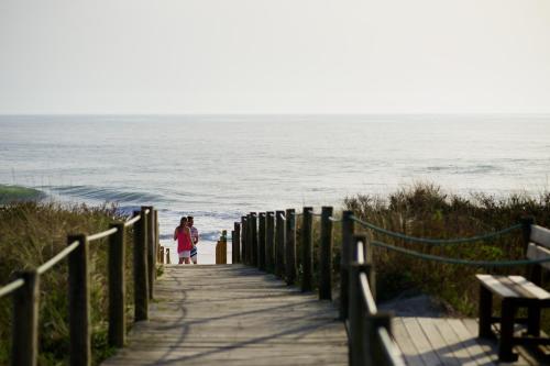 a woman walking down a wooden path to the beach at Quinta do Monteverde in Viana do Castelo