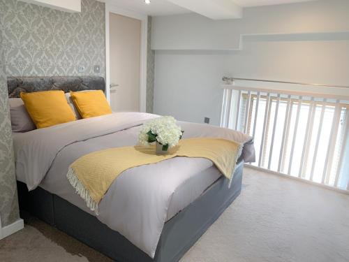 a bedroom with a bed with yellow pillows and flowers at Duplex 2-bedroom apartment in Liverpool centre in Liverpool