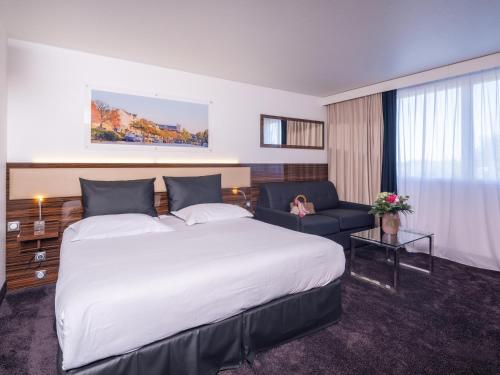 una camera d'albergo con un grande letto e un divano di Westotel Nantes Atlantique a La Chapelle-sur-Erdre