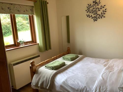 a bedroom with a bed with two green pillows on it at Ty Twt - complete holiday home in Llandysul