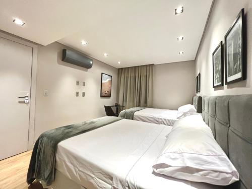 a hotel room with two beds and a television at Flat novo, 2 quartos, garagem no coração dos Jardins in São Paulo