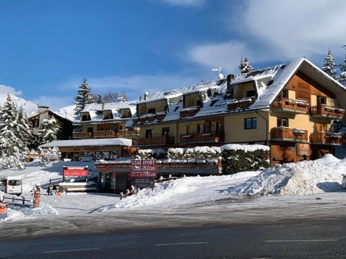 un grande edificio con la neve sopra di esso di Appartamenti & Wellness Piero Gros a Sauze d'Oulx