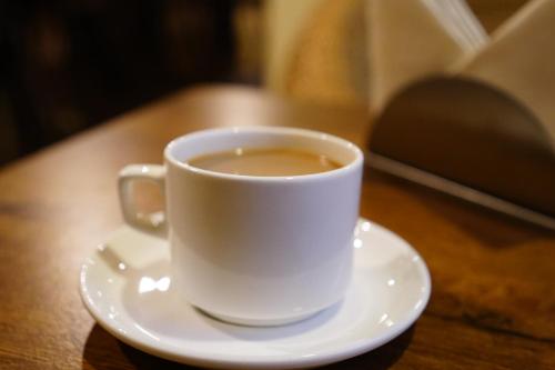 a white cup of coffee on a plate on a table at Hotel White Lotus Gangtok in Gangtok