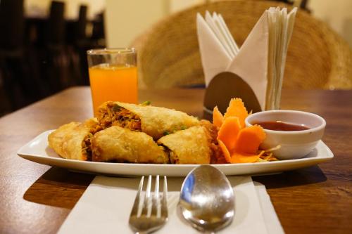 a plate with a sandwich and chips and a glass of orange juice at Hotel White Lotus Gangtok in Gangtok