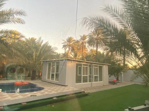 a small house with a pool and palm trees at Dar Al Hamra Rest إستراحة دار الحمراء in Al Ḩamrāʼ
