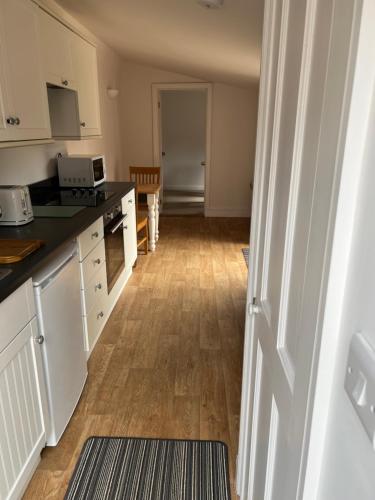 a kitchen with white cabinets and a wooden floor at The Old Dairy Steep,Petersfield in Collyers Estate in the South Downs National park in Petersfield