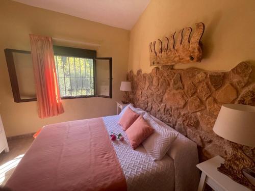a bedroom with a bed and a stone wall at Cortijo de las cañadas in Venta de Mendoza
