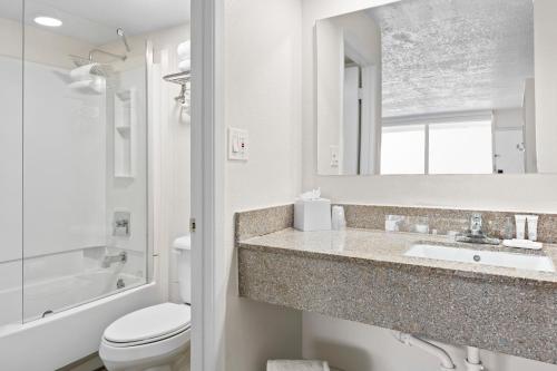 Baño blanco con lavabo y aseo en Developer Inn Maingate, a Baymont by Wyndham en Kissimmee