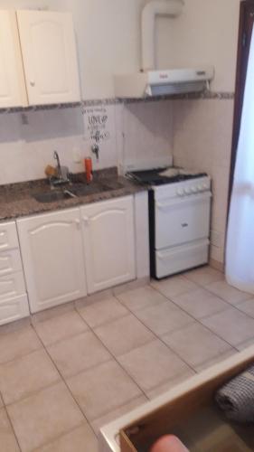 a small kitchen with white cabinets and a stove at Departamento Dorrego in Trenque Lauquen