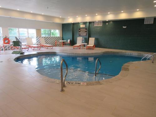 a swimming pool in a hotel lobby with chairs and tables at Holiday Inn & Suites McKinney - N Allen by IHG in McKinney