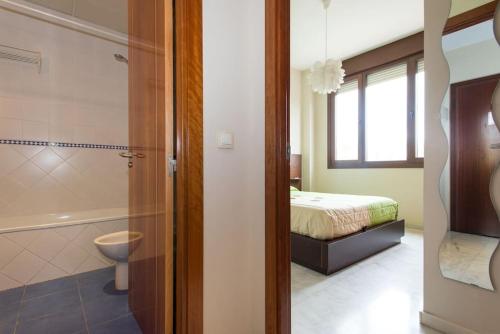 y baño con cama, ducha y aseo. en FIBES con parking gratis. Apartamento Sevilla Este., en Sevilla