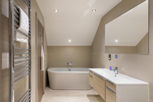 a bathroom with a white tub and a sink at The Kilnwick Percy Resort and Golf Club in Pocklington