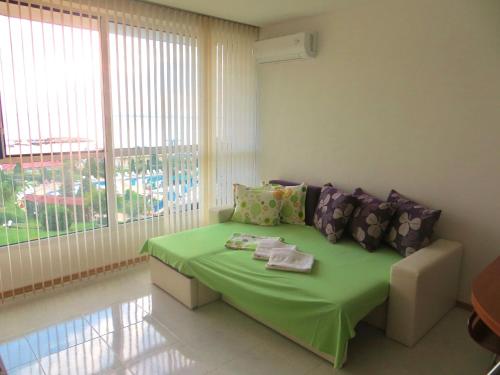 Pokój z zielonym łóżkiem i dużym oknem w obiekcie Holiday Apartment in Riviera Complex w Swetim Własie