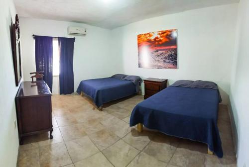 a bedroom with two beds and a table and a painting at Casa Ferriño in Cuatrociénegas de Carranza