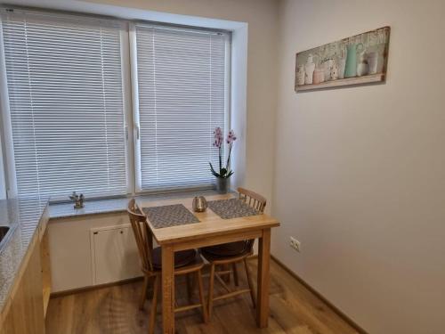 Neris apartments في شياولياي: مطبخ صغير مع طاولة وكراسي خشبية