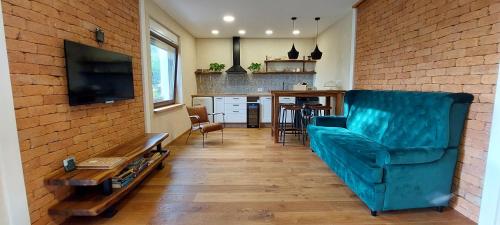 uma sala de estar com um sofá azul e uma cozinha em Olivea em Dobrovo