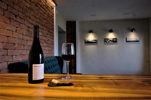 una botella de vino y una copa sobre una mesa de madera en Olivea en Dobrovo