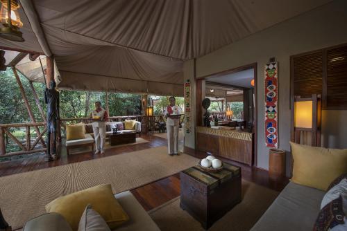 a living room with two people standing in a tent at Neptune Mara Rianta Luxury Camp - All Inclusive. in Masai Mara